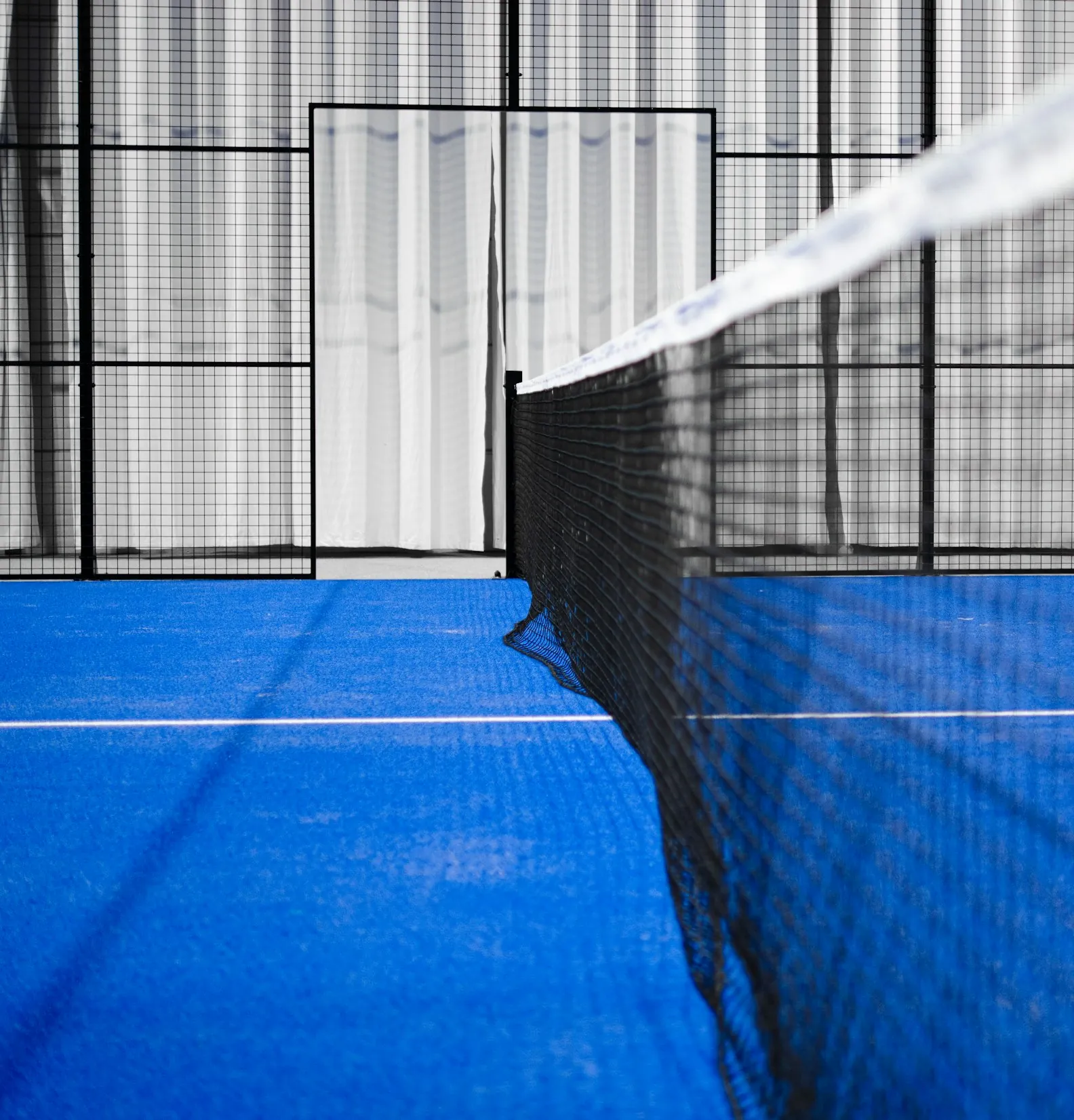 Close view along the net of a padel court, blue surface and mesh
